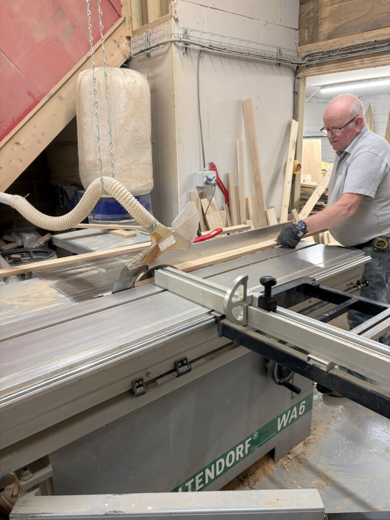 Charles Edwards craftsman operating an Altendorf panel saw to cut solid oak timber in the workshop